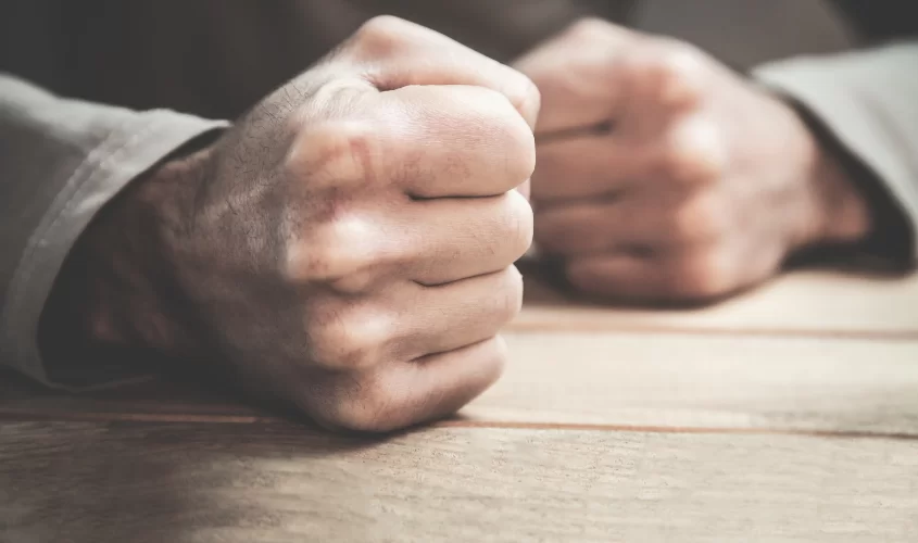 Fits clenched on table symbolizing anger