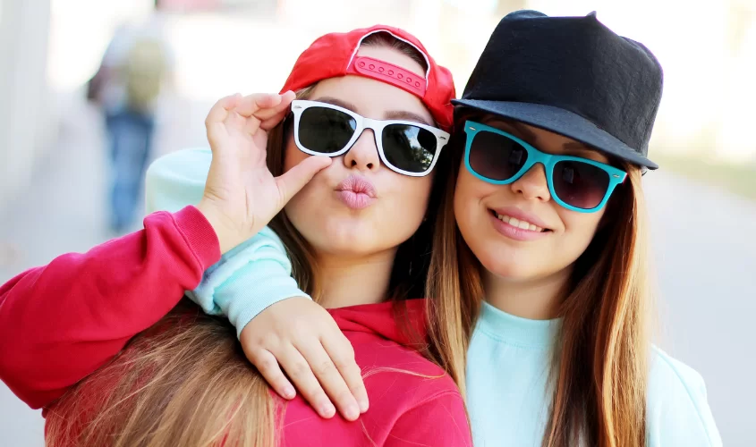 Teen girls wearing hats and sunglasses, posing for a picture