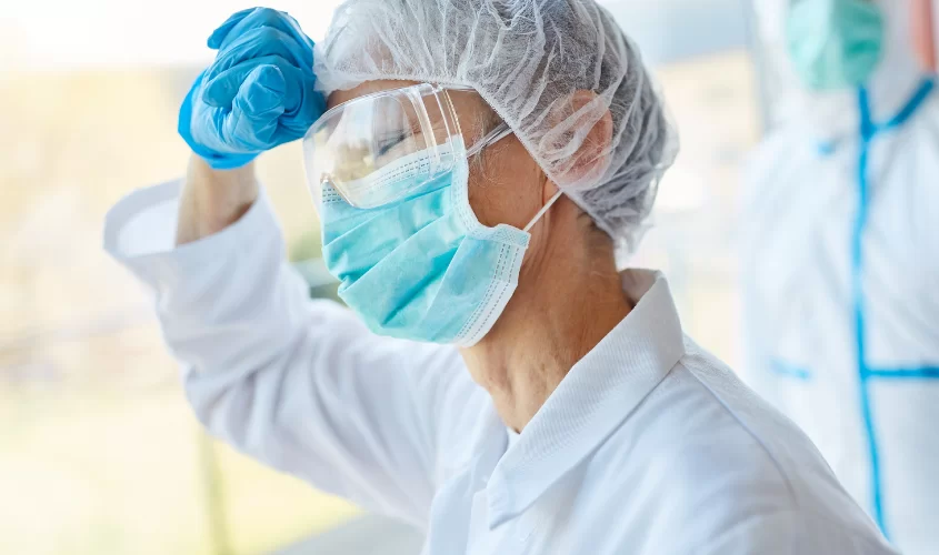 Healthcare worker wearing a mask, gloves, and protective gear