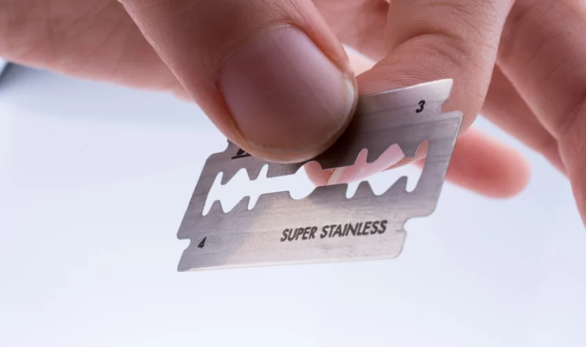 Individual holding razor blade symbolizing self harm