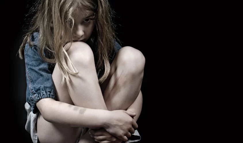Child with knees pulled into chest symbolizing trauma, abuse, and difficult times