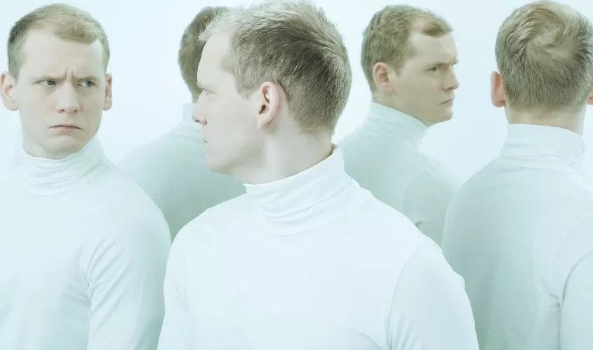 Man looking in mirror seeing different versions of himself