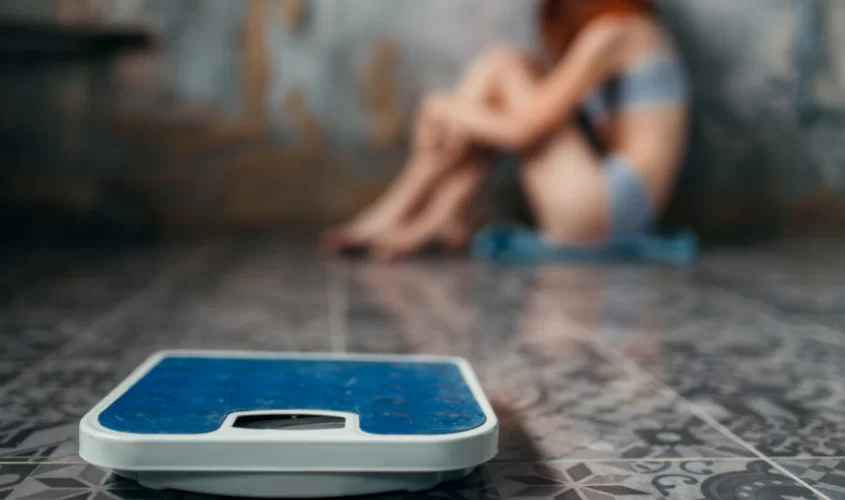 Scale with woman sitting on floor in the back
