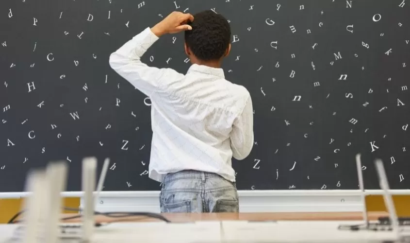 Child looking at bored with letters all mixed up symbolizing dyslexia