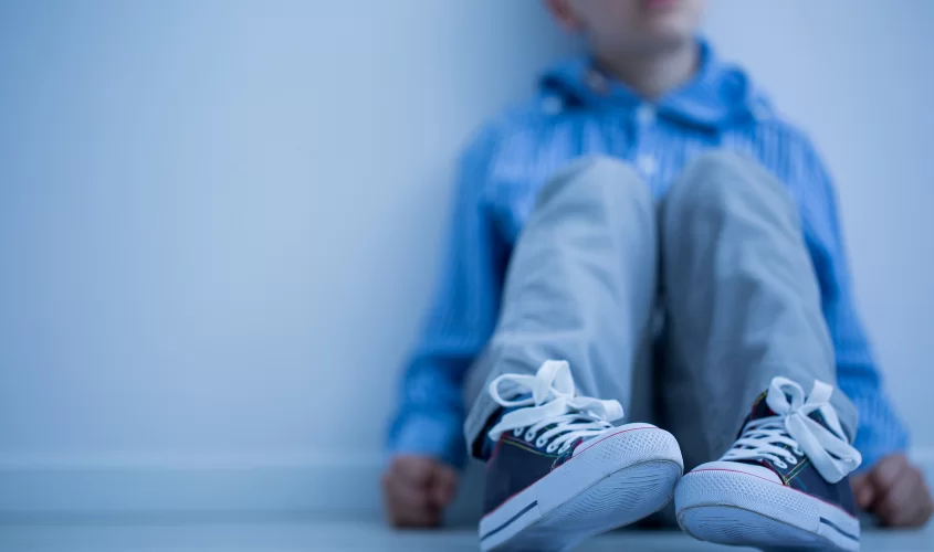 Child sitting down by a wall