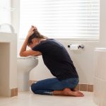 Woman sitting on ground over toilet