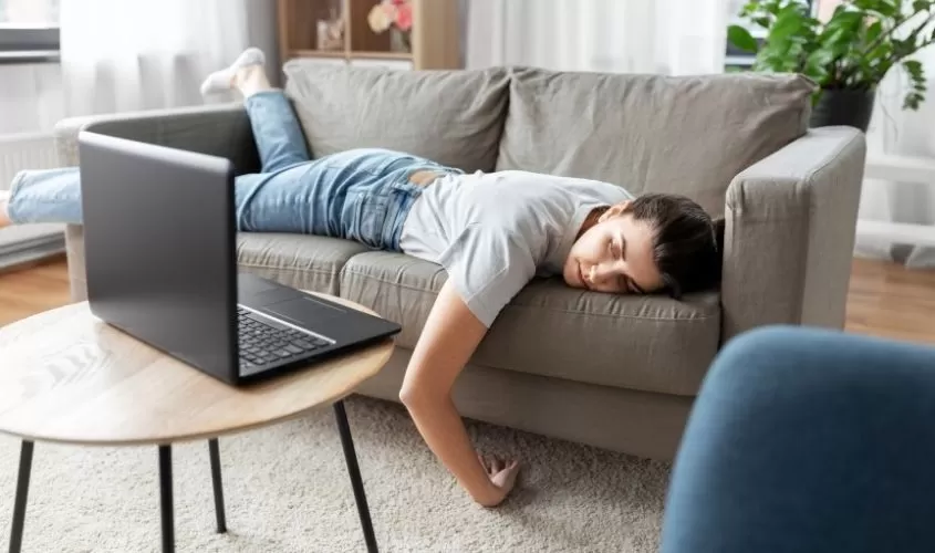 Woman laying on couch staring at open laptop