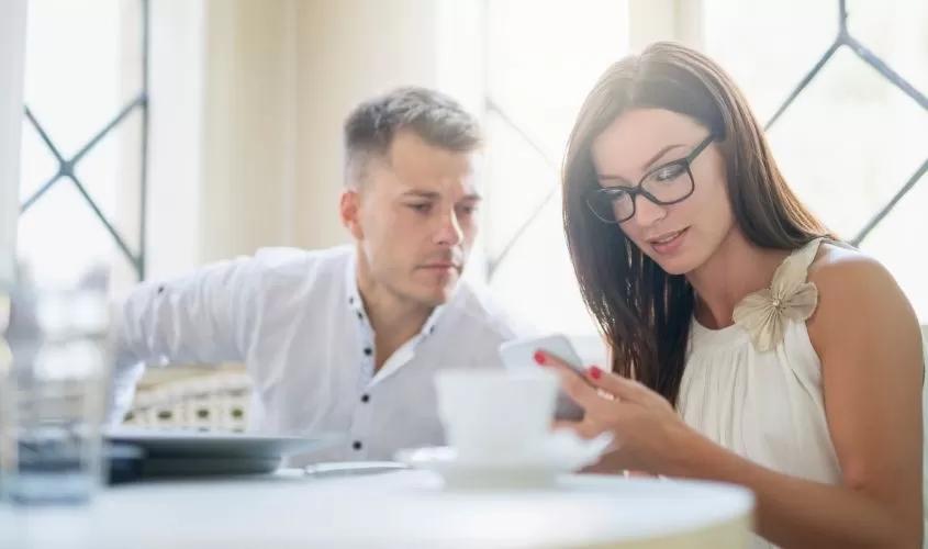Man looking over shoulder at women on her phone