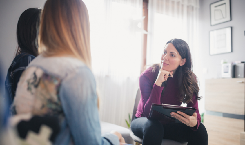 Female therapist speaking to same-sex couple.