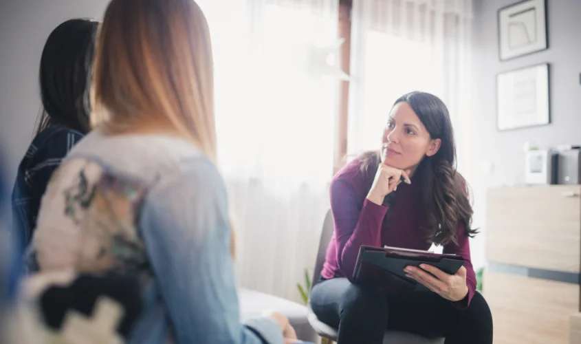 Female therapist speaking to same-sex couple.