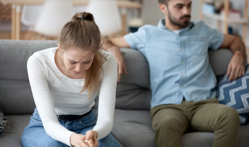 Woman upset sitting on couch with man behind her