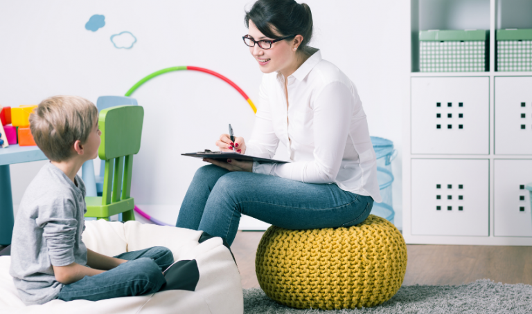 young child sitting with adult therapist