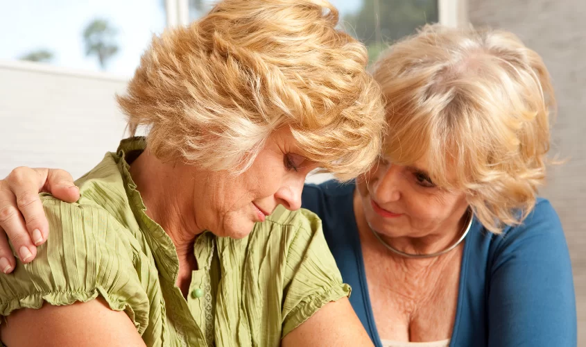 Woman wrapping arm around another woman to symbolize support