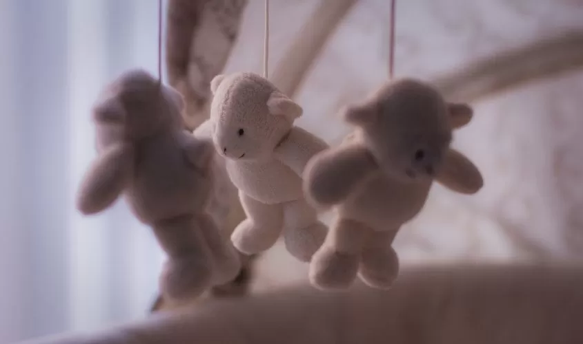 Soft teddy bear mobile hanging over an empty crib