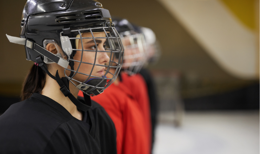 Female hockey player listening to her coach speak.