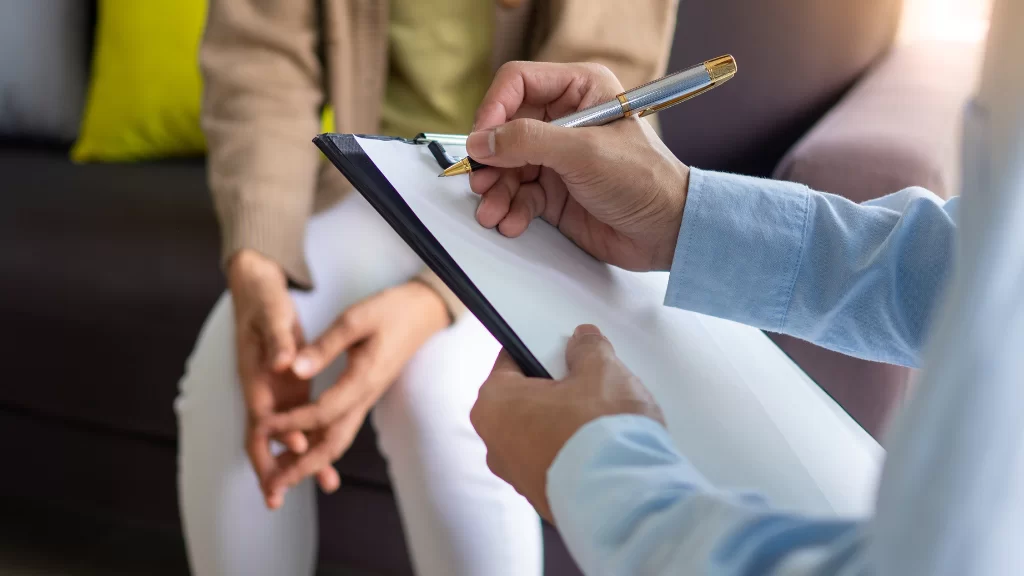 Therapist taking notes on a clipboard during a session with a client