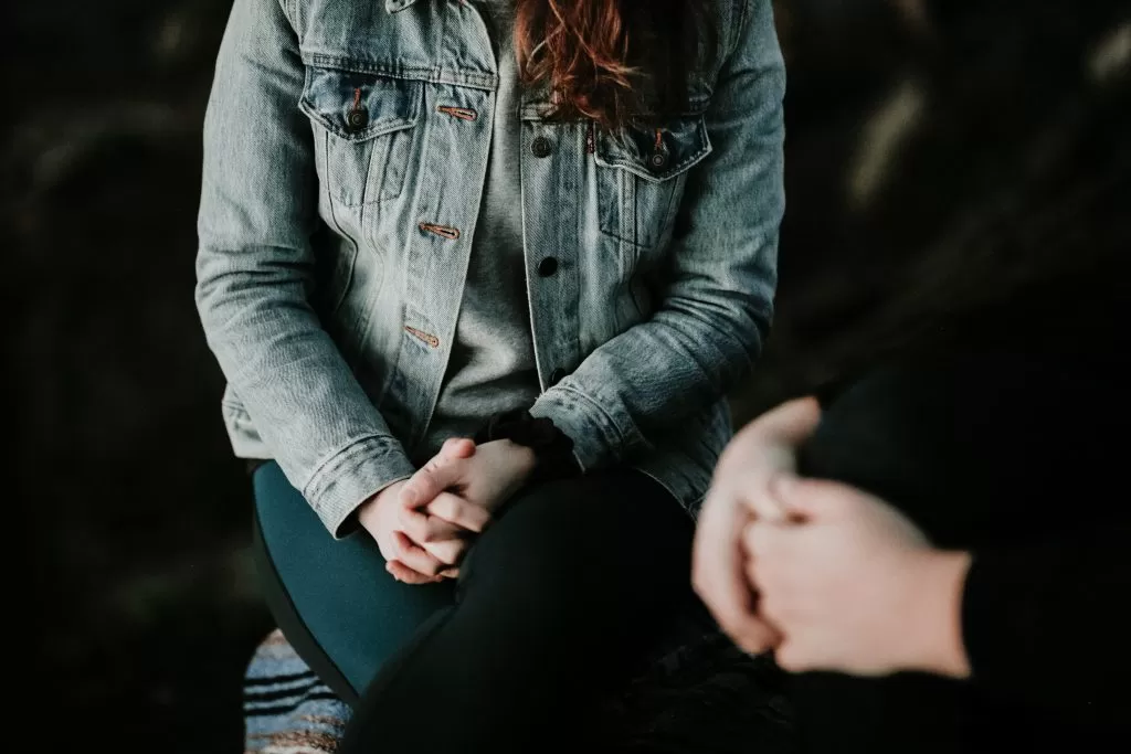  two people sitting with hands clasped
