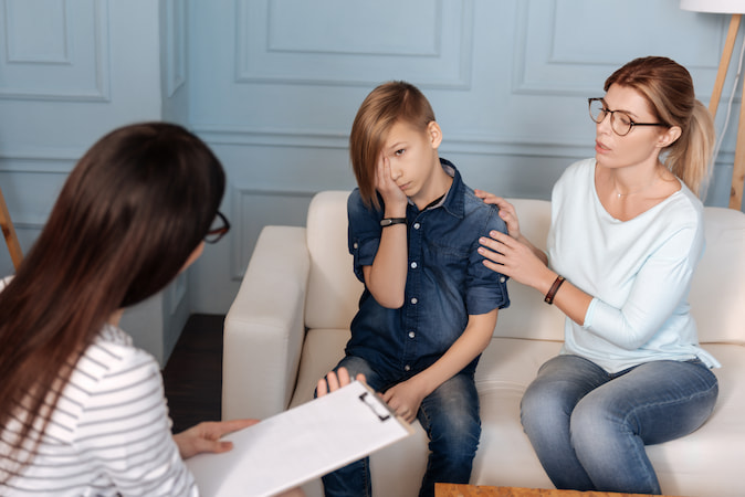 Mother calming down his son while talking to a psychologist