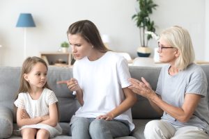 Young mother scolding her young daughter while grandma tries to interfere