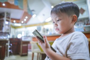 Small kid holding and watching something on a mobile phone