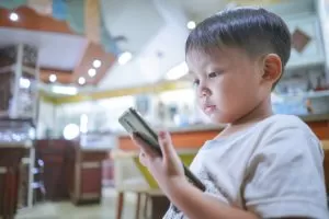 Small kid holding and watching something on a mobile phone