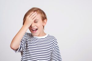 Young boy slapping his palm to his head in frustration or anger