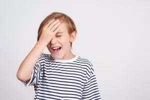 Young boy slapping his palm to his head in frustration or anger