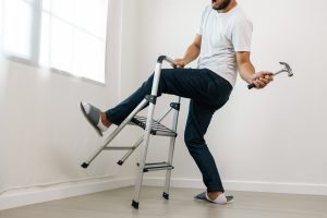 Man falling down and getting stuck in a stepladder