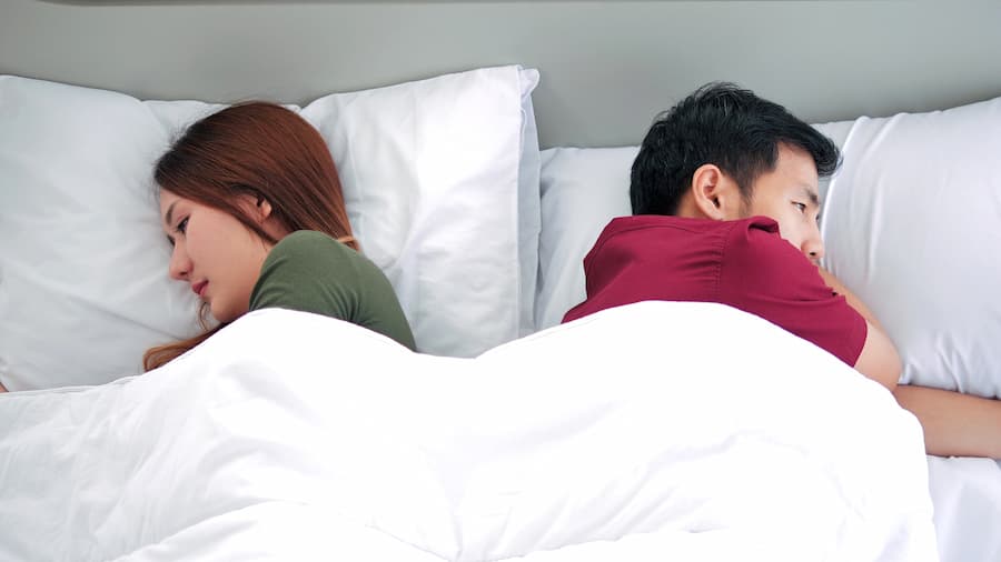 unhappy asian couple lying in bed