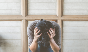 Person sitting with head in hands.