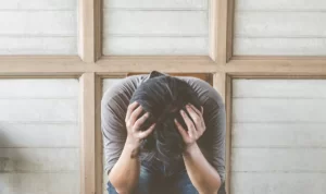 Person sitting with head in hands.