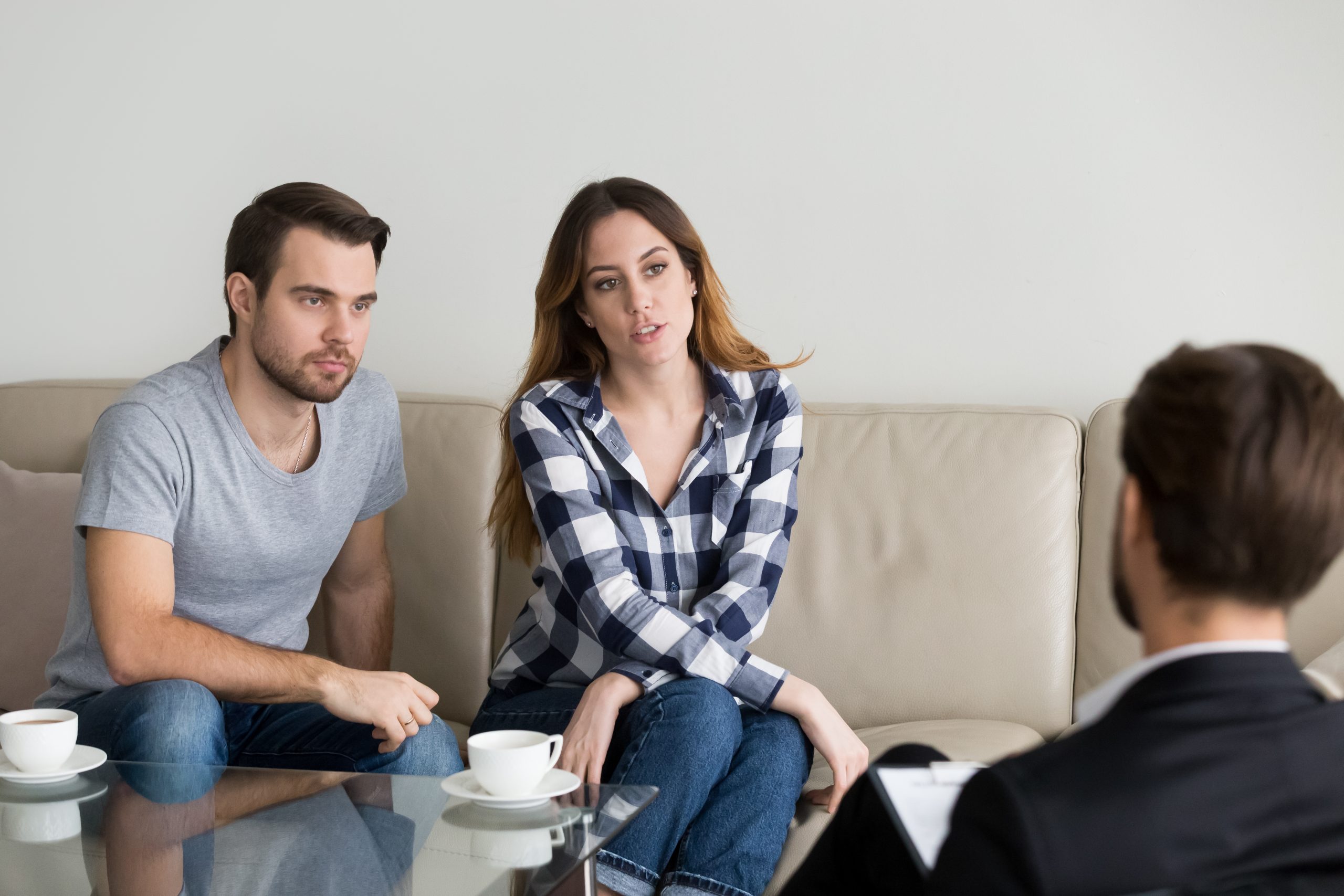 Unhappy Millennial Couple Talking To Psychologist Sitting On Couch