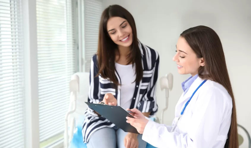 Doctor and patient smiling and discussing results in a bright medical office.