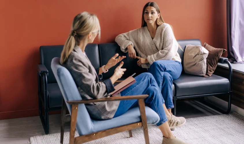 Two women engaged in a one-on-one therapy session in an office space