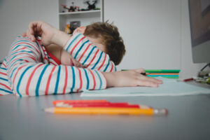 Child tired and bored of doing homework, kid stressed from learning indoors