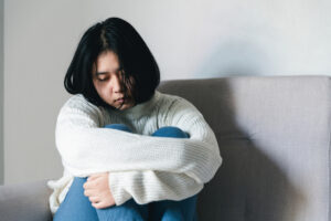 Concept of sad teenage girl depression. Upset teenage girl sitting at window indoors. Anxiety young woman Despair and stress. Lonely and unhappy female are social victims. loneliness youth in home.