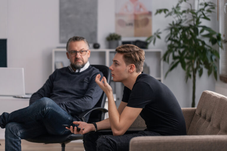 Professional psychologist and teenager explaining his problems during therapy