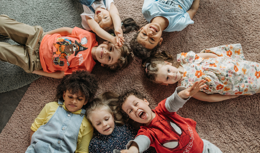 Children laying in a circle playing.