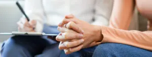Close-up of a person’s hands clasped together during a therapy session.