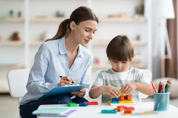 A therapist helping a child build with blocks during a session.