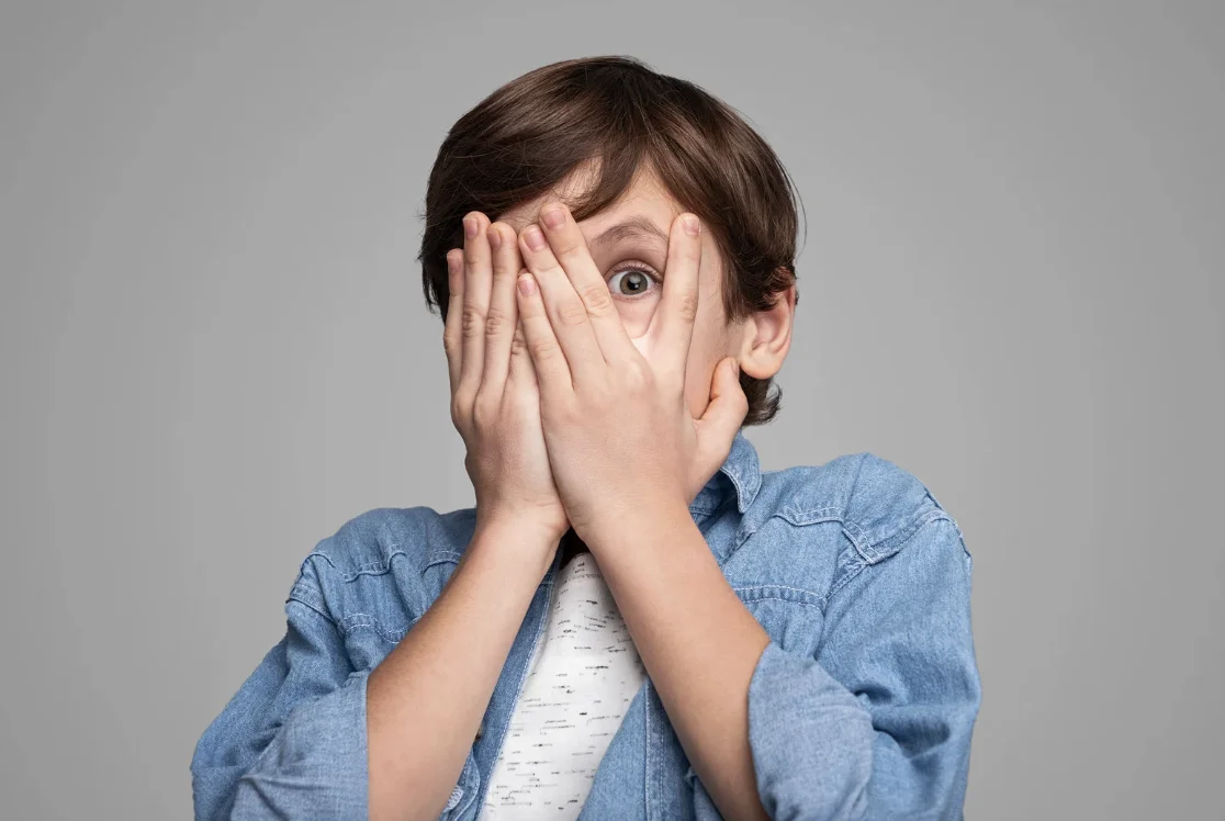 Scared child peaking out of his hands