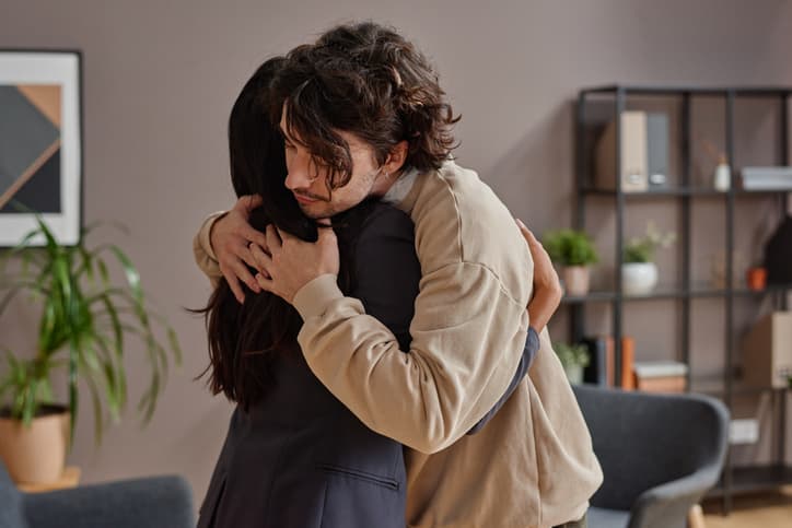 Two adults sharing a supportive hug in a counseling office or therapy setting, expressing empathy, comfort, and emotional connection during a difficult moment.